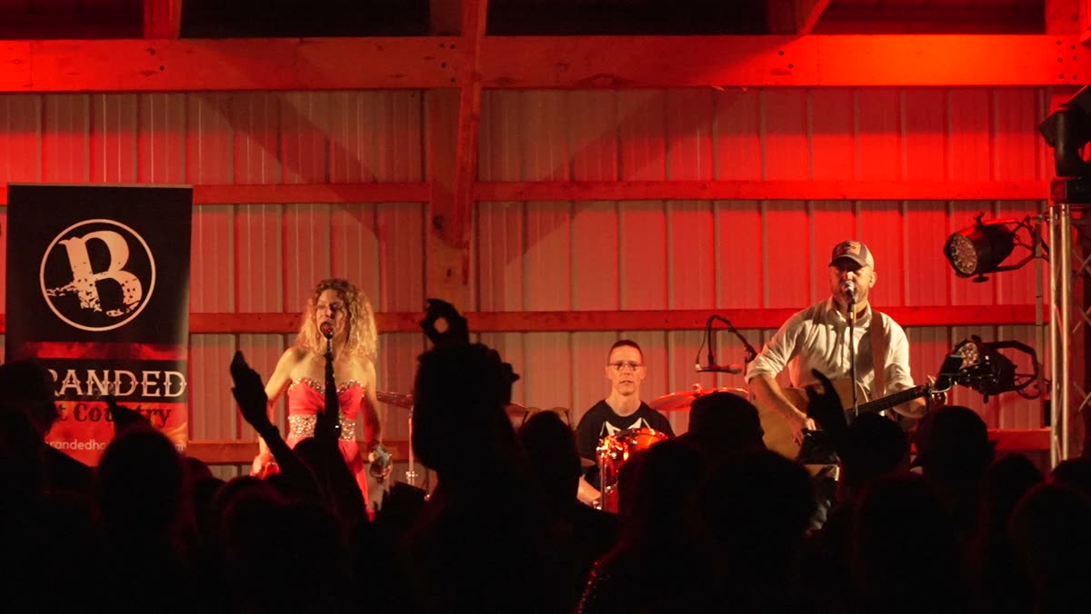 Packed crowd under red stage lights in the barn at Bluff Valley